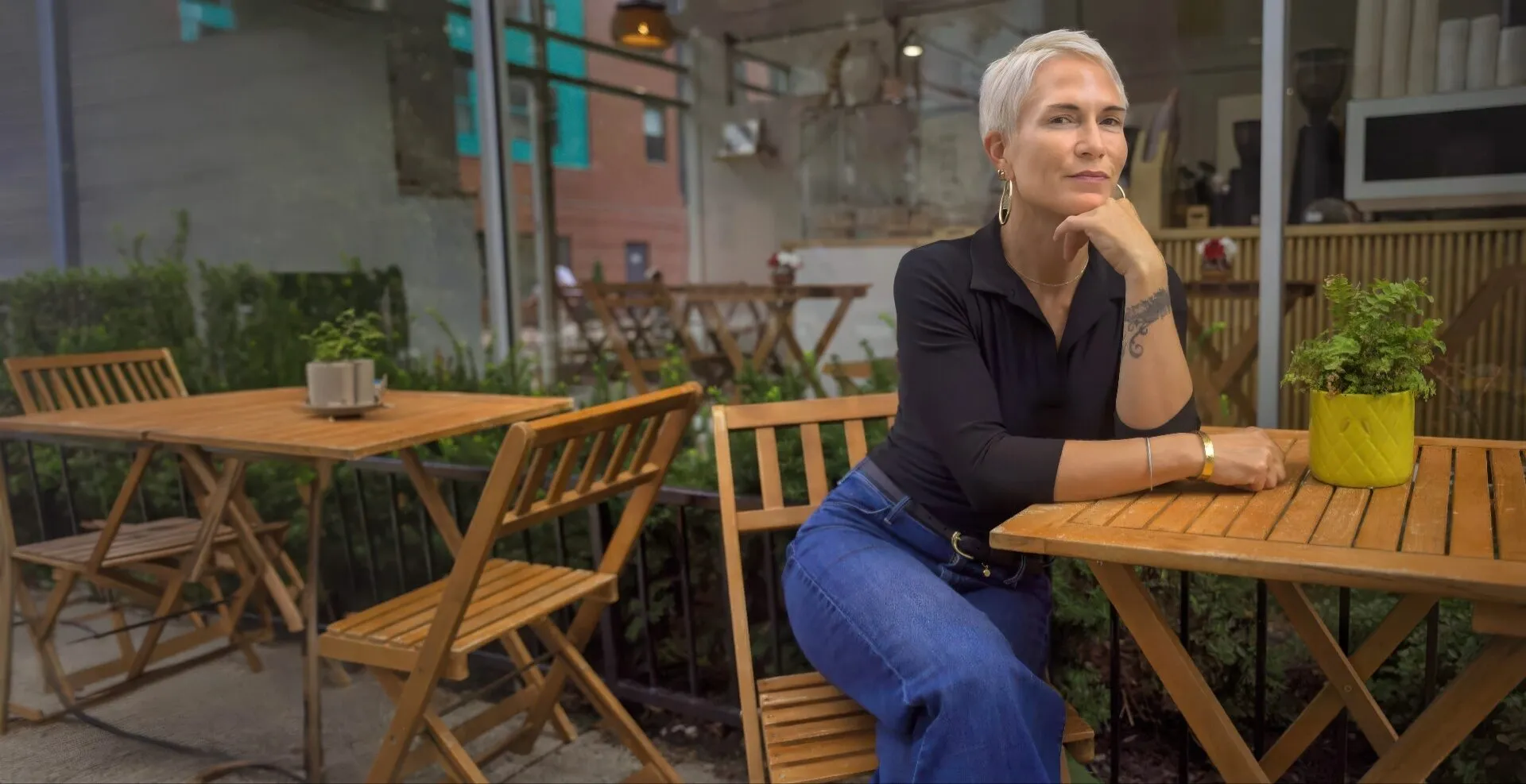 Mari Gardner seated at an outdoor cafe table, chin resting on her hand